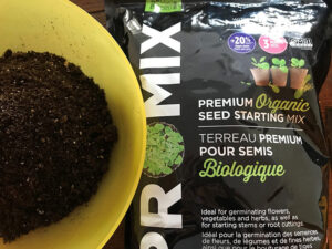 a bucket with soil and a bag of pro mix seed starting mix